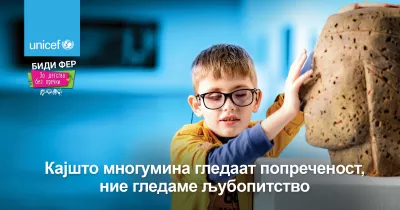 A billboard depicting a child with visual impairment exploring a statue with his fingers and arms, with the message - Where some see a disability, we see a curiosity