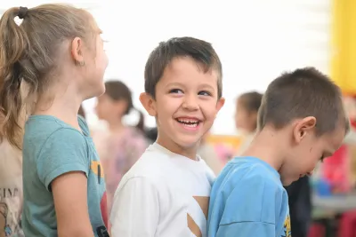 Boy smiling and standing in line with friends in kindergarten 
