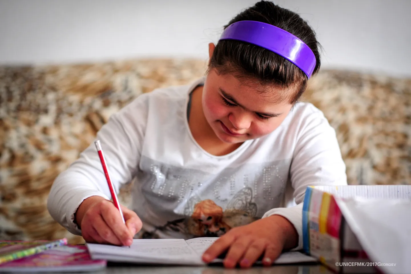 12 year old Stefanija who has down syndrome writes down in her notebook in the living room of her family house in Delcevo
