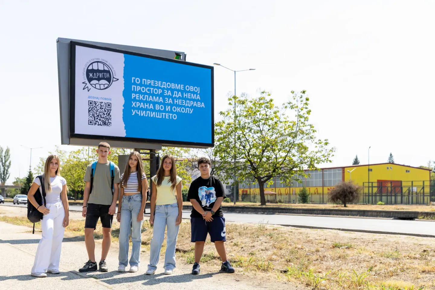 Group of adolescents standing in front of a billboard with a message 