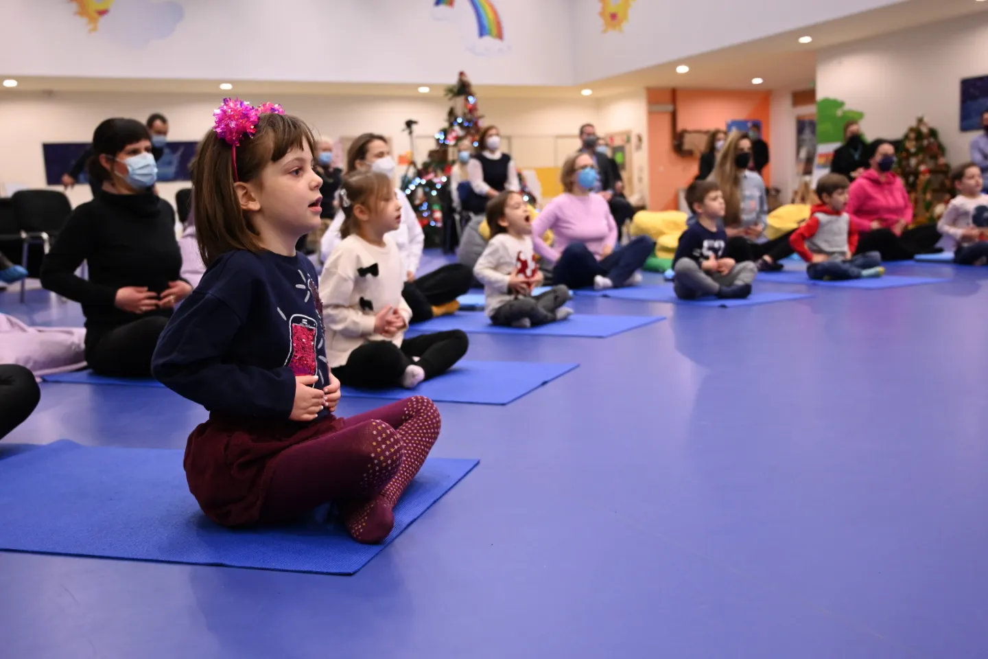 Kindergarten children doing breathing exercises together with their parents 