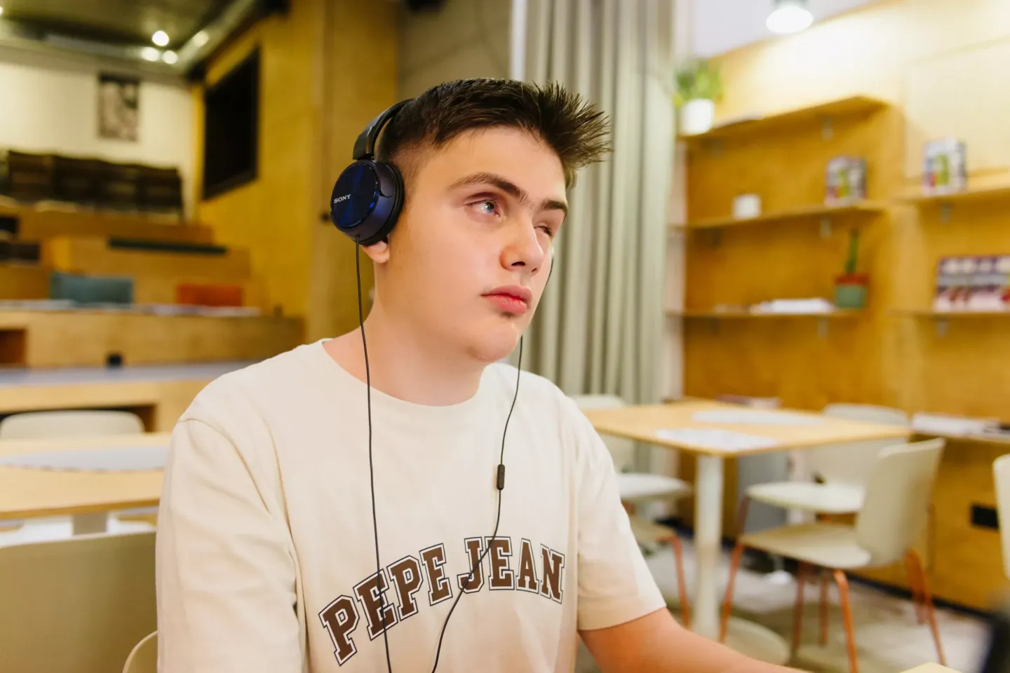 Filip sitting in a cafe working on a laptop with an audio reader