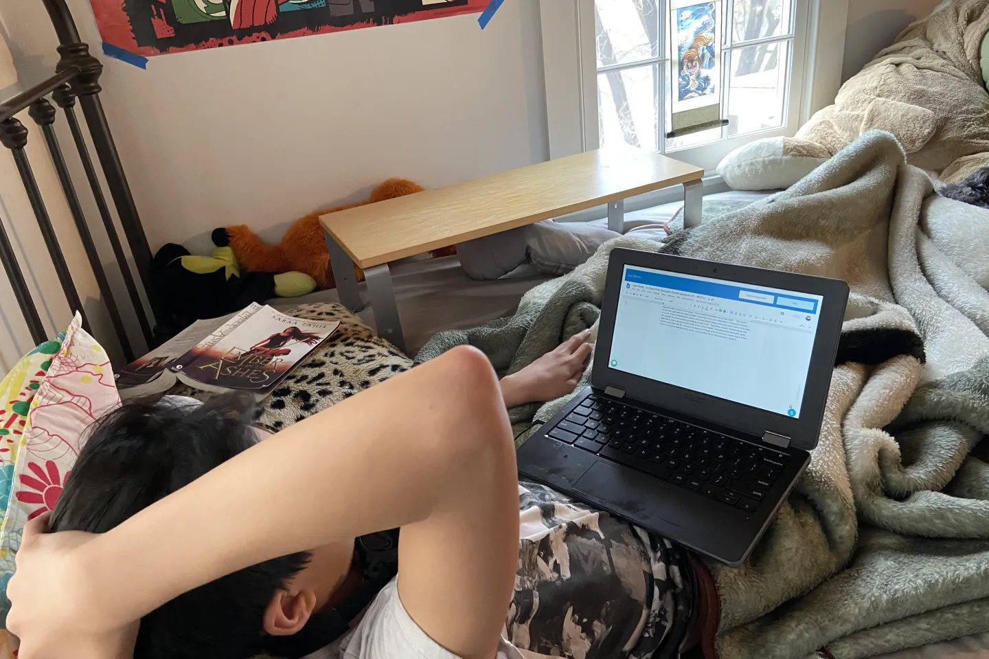 Adolescent boy in bed following an online class on his laptop 