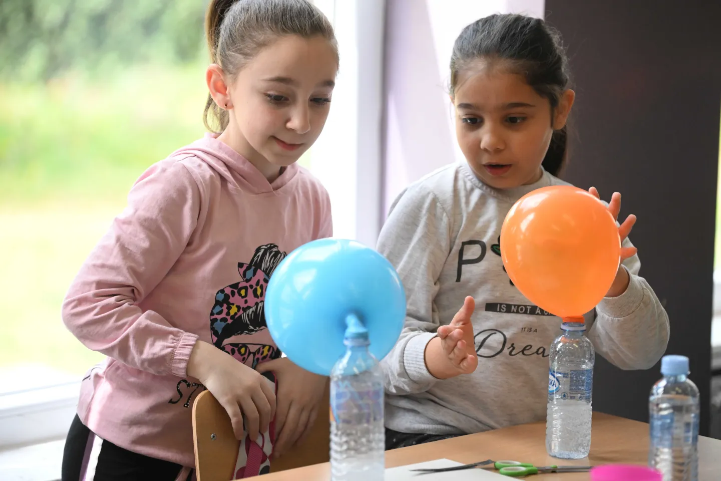 Two fourth grade students compare their results after an experiment with baking soda and vinegar mixed together releasing carbon dioxide.