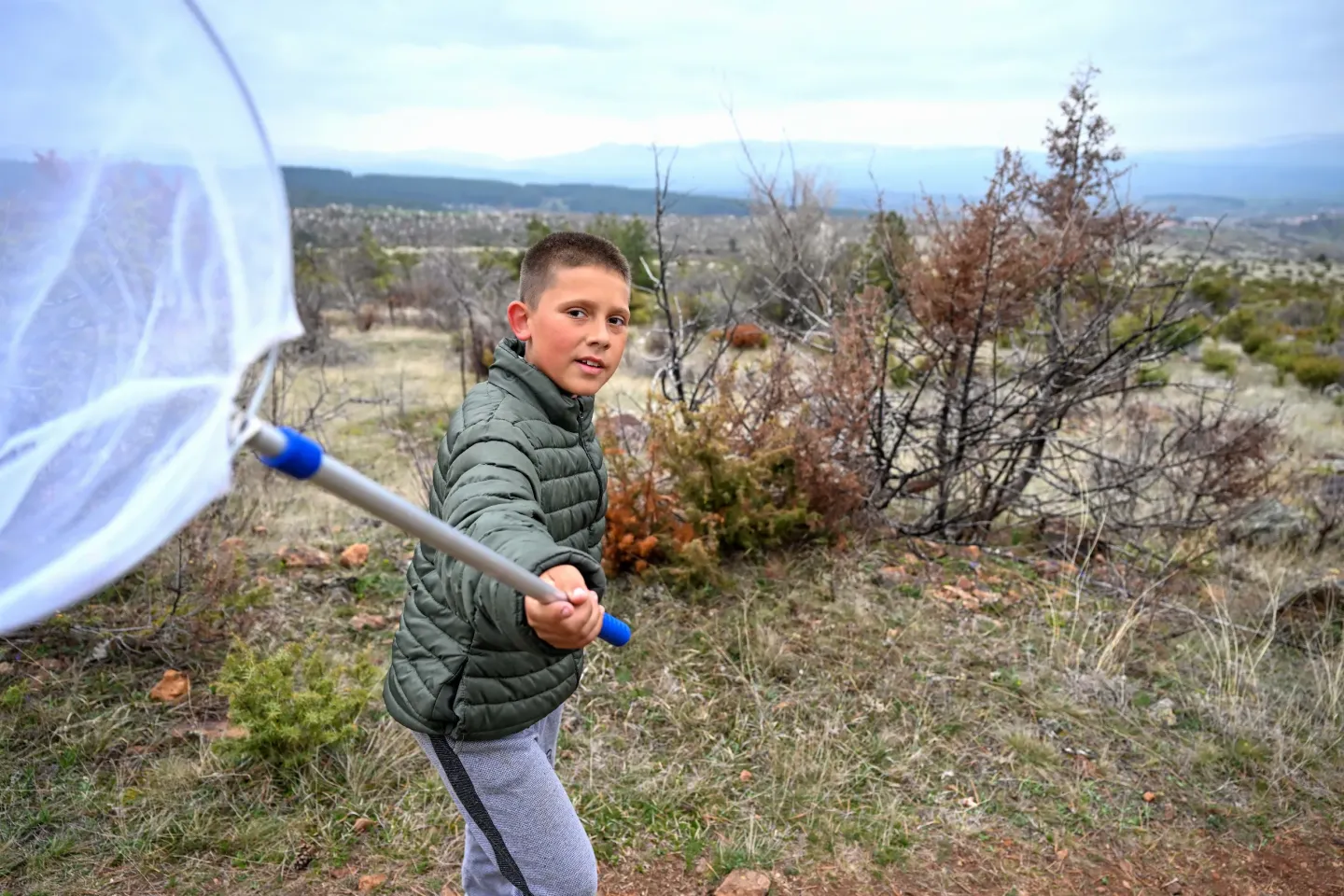 Boy on a field trip holding a net to catch and observe insects