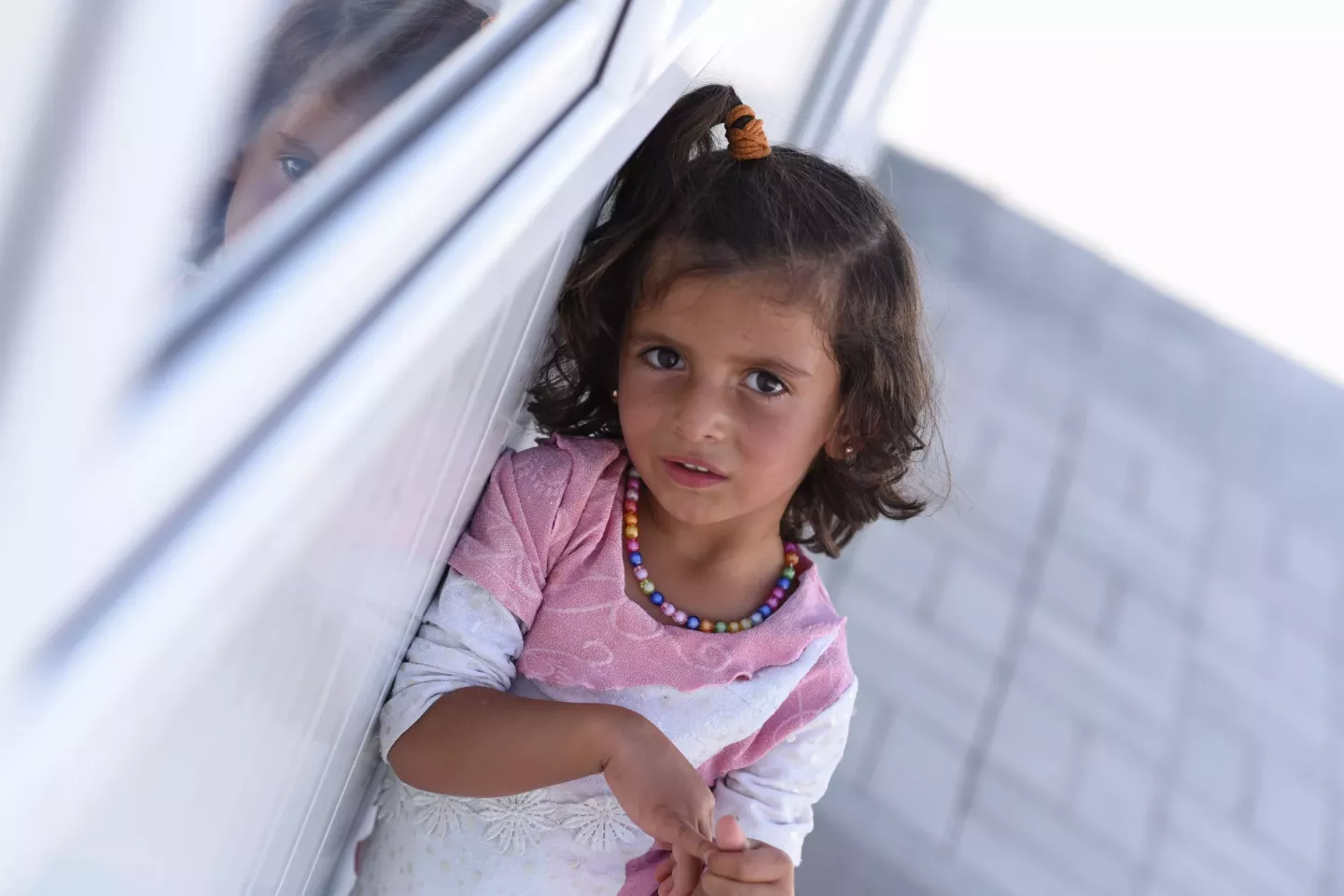Girl wearing pink blouse and necklace looking at the camera