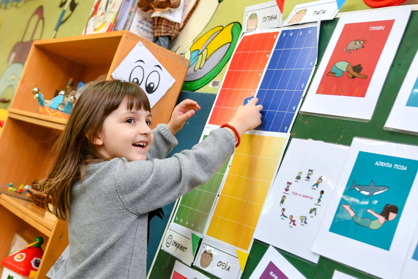 A girl interacting with a  poster about recognizing emotions