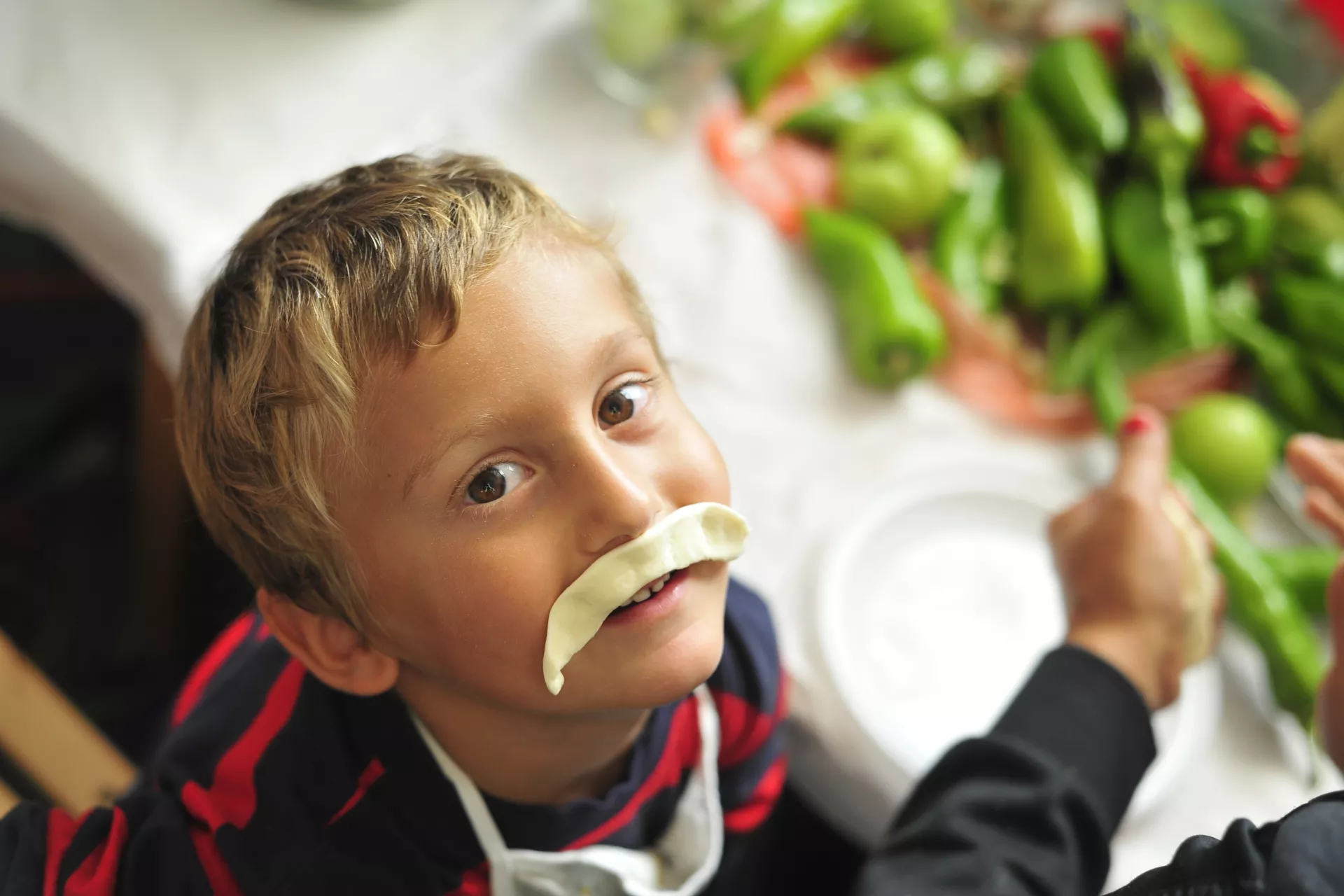 Photo of a child with a moustache made from dough during kindergarten classes focused on nutrition and food preparation