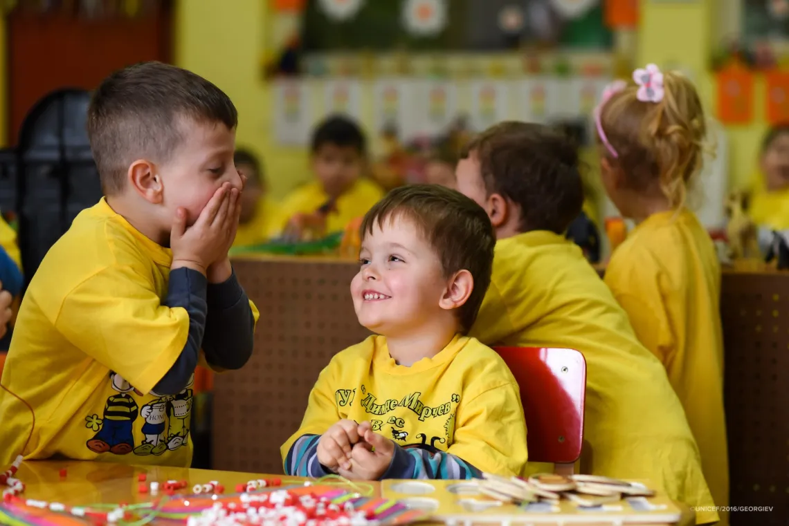 Two boys aged 4 laugh while playing with puzzles in kindergarten