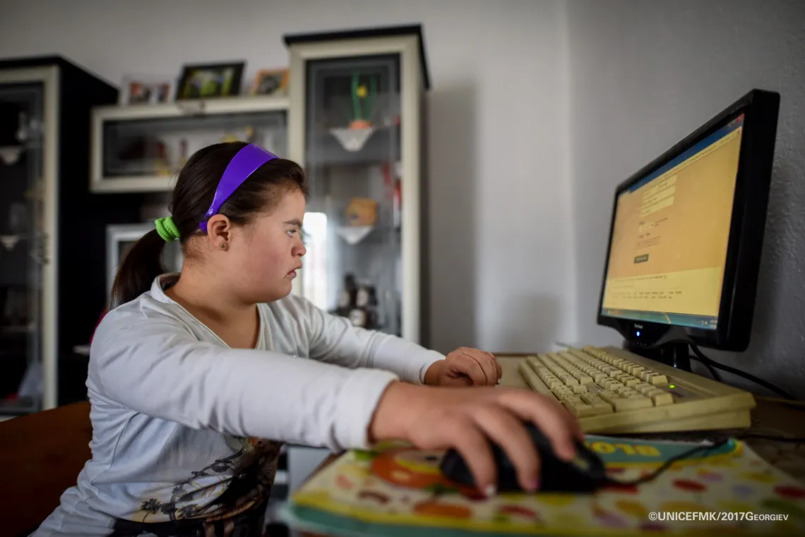 12 year old Stefanija who has down syndrome uses her computer to listen to some music in the living room of her family house in Delcevo