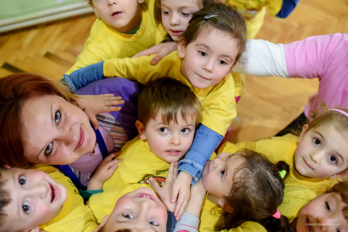 A group of children in kindergarten along with their teacher surround and hug their friend Mihail (4 years old) who has a cerebral palsy