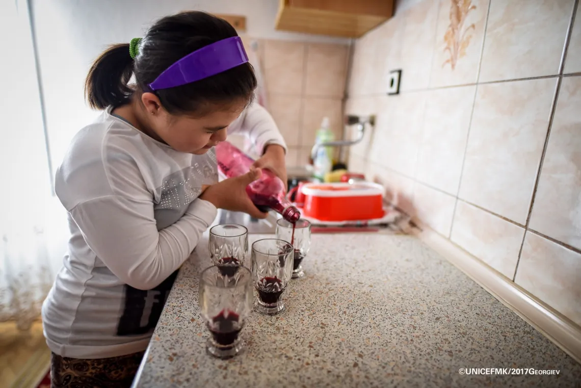 Stefanija 12 year old girl with down syndrome helps out in the kitchen by pouring some homemade juice 