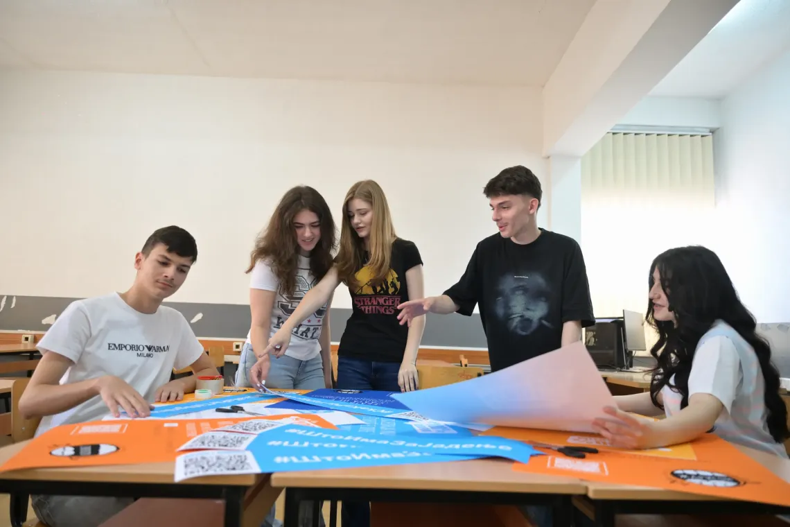 Group of adolescents looking at posters with messages and data on food environments in schools