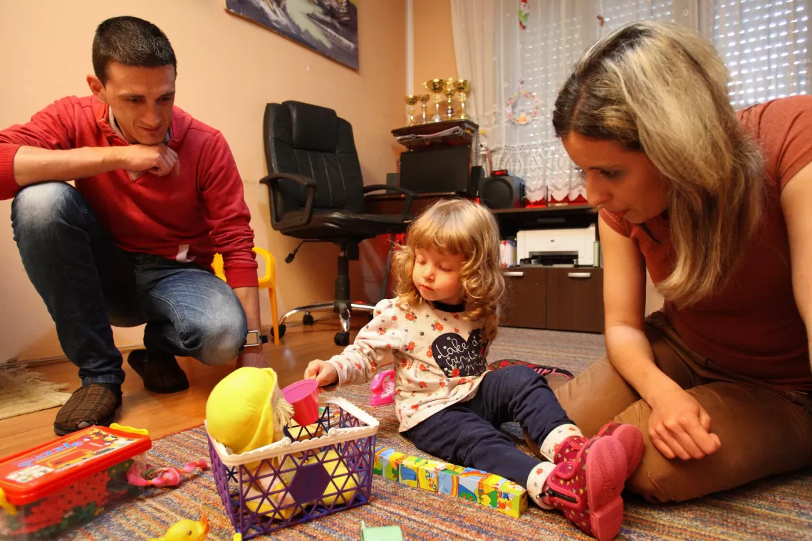Tea (2.5 year old) playing with her mother and father in their living room.  UNICEF in Serbia is focused on supporting the Ministry of Health to establish and provide access to quality services that contribute to young childhood survival and development. Our work is focused on improving the prenatal, paediatric and community nursing services for early detection of risks that cause children to lag behind in their development, early intervention, and support for children and their families.