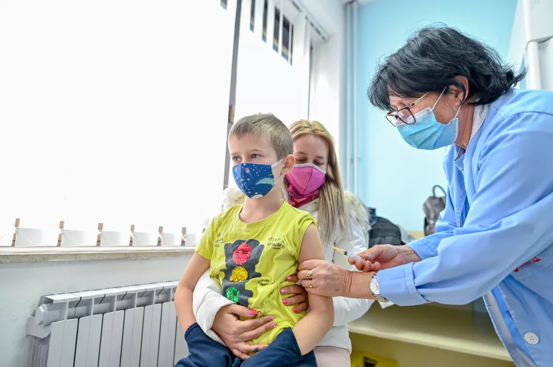 A boy sitting in his mother's lap while receiving his vaccine 