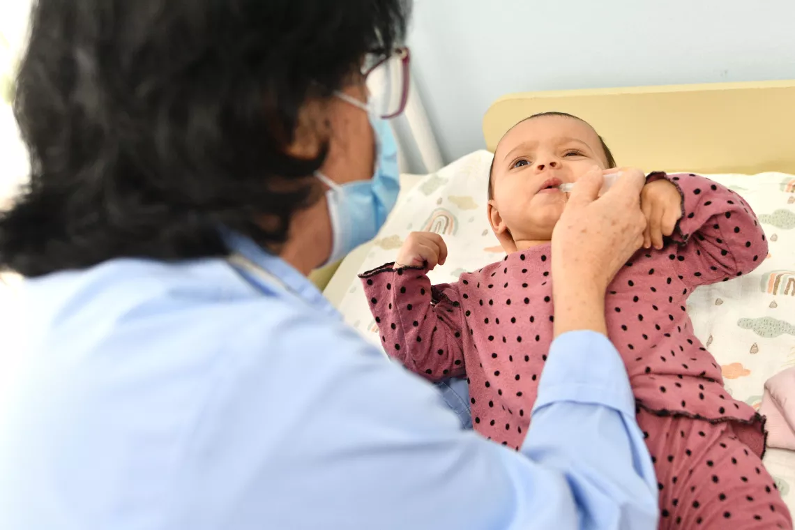Pediatrician administering oral vaccine to a baby girl 