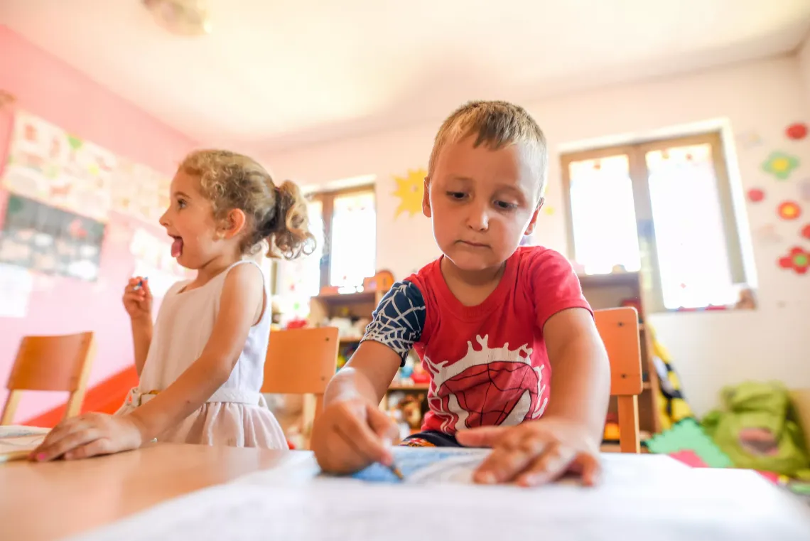 Boy drawing and girl making funny faces 
