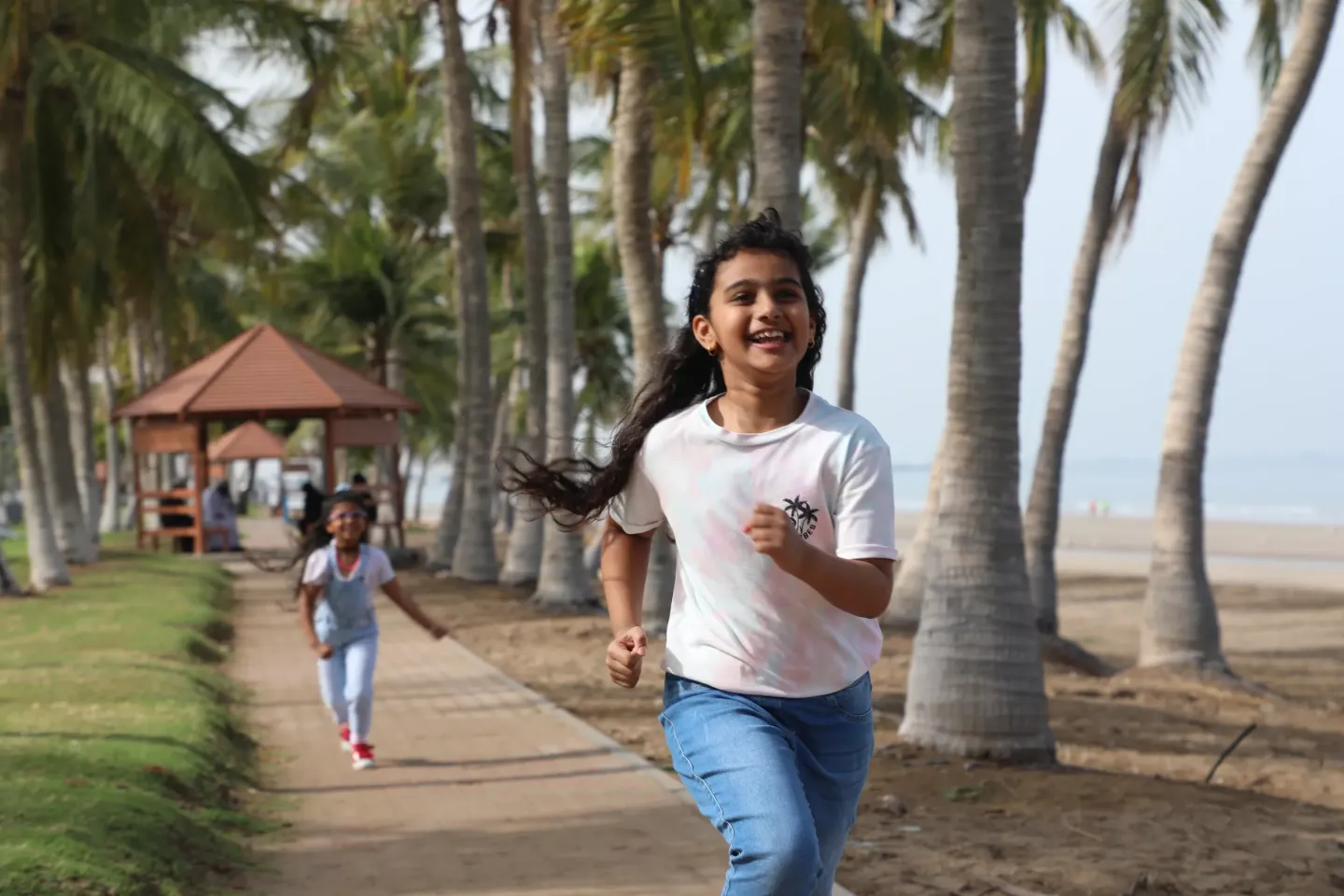 A girl smiles while running near the beach 