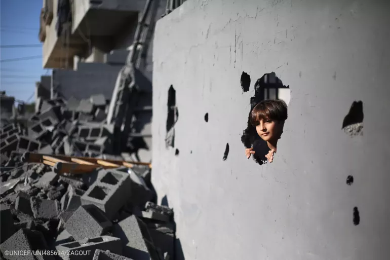A Palestinian child, looking from the rubble of his house. 