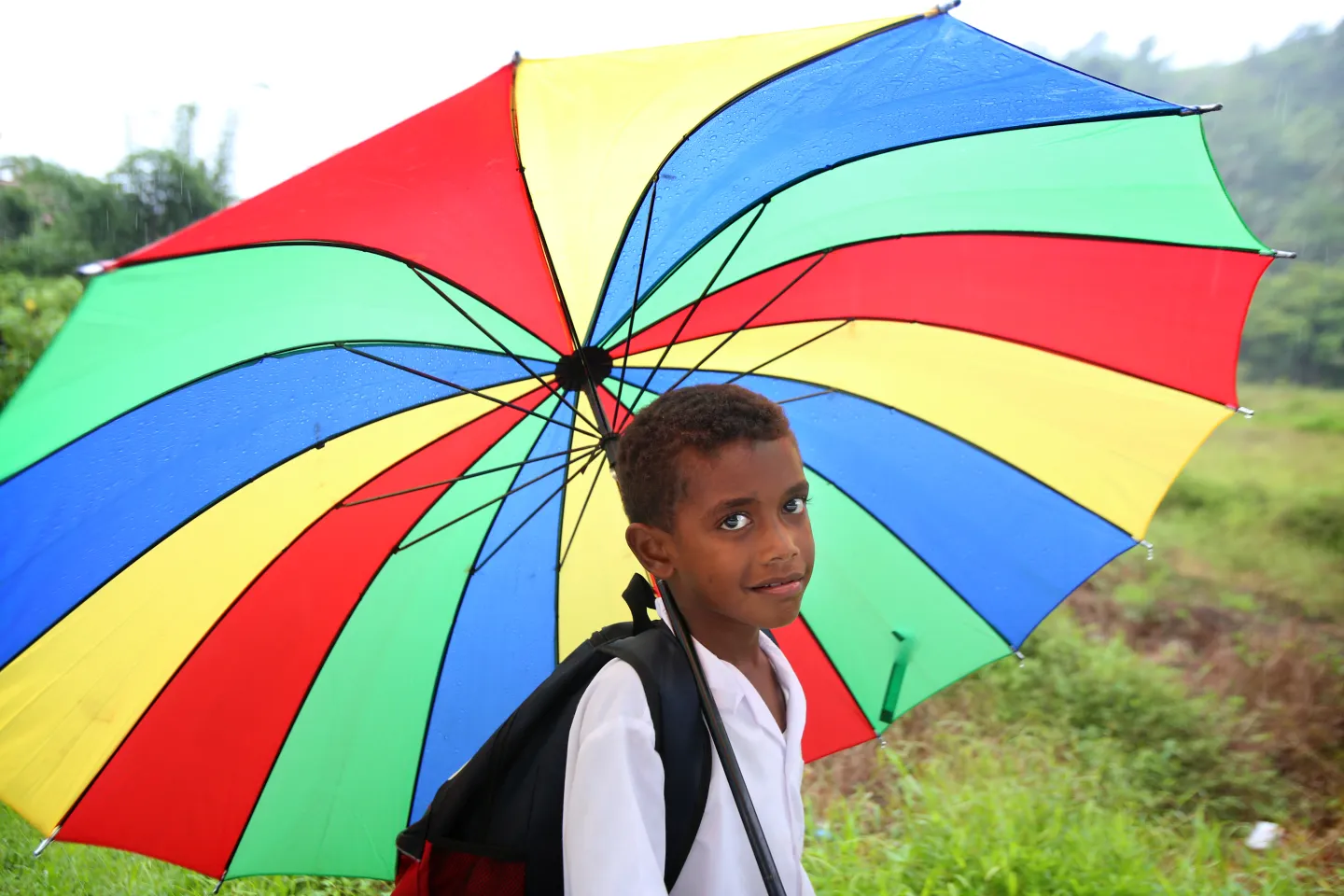 A boy holding a multi-color umbrella.
