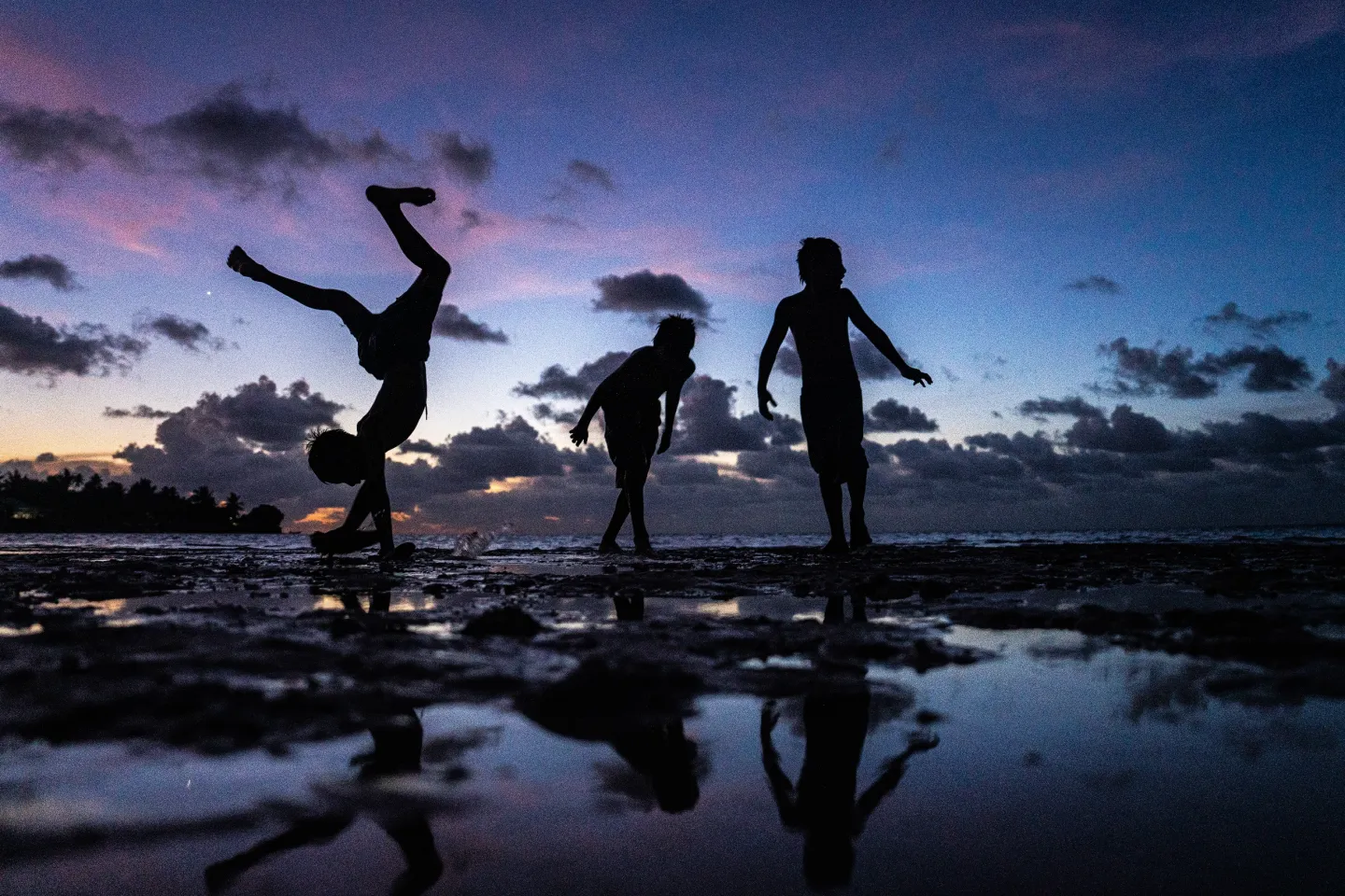 Children playing by the sea at sunset in Kiribati