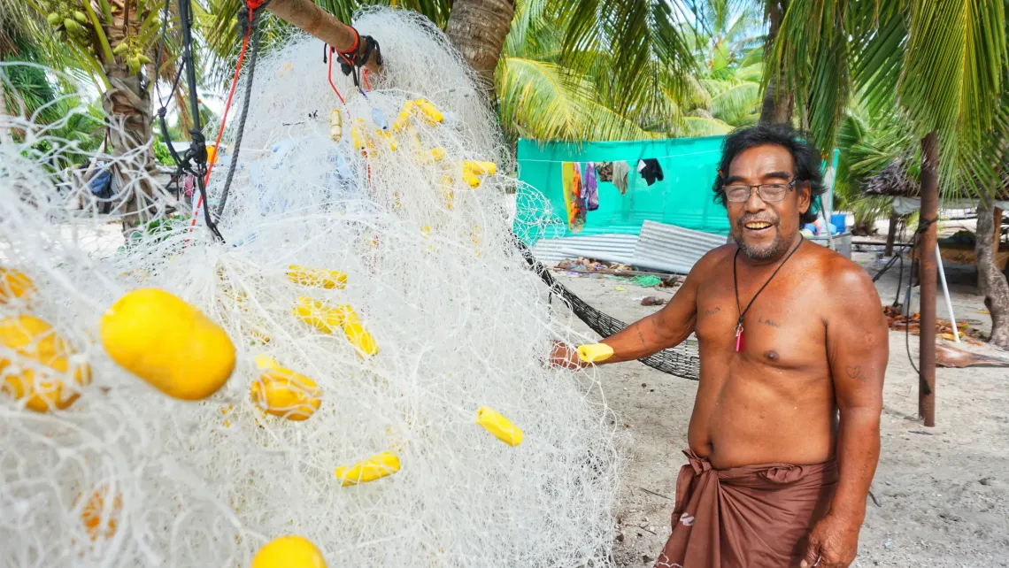 Kianteroro, a fisherman from Kiritimati Island in Kiribati, stands with his net on the beach.