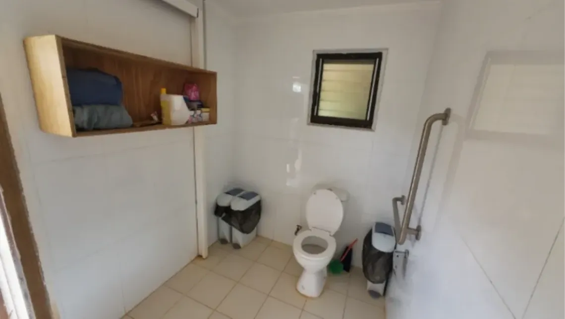 A school bathroom, with a shelf for MHM products and sanitary bins.
