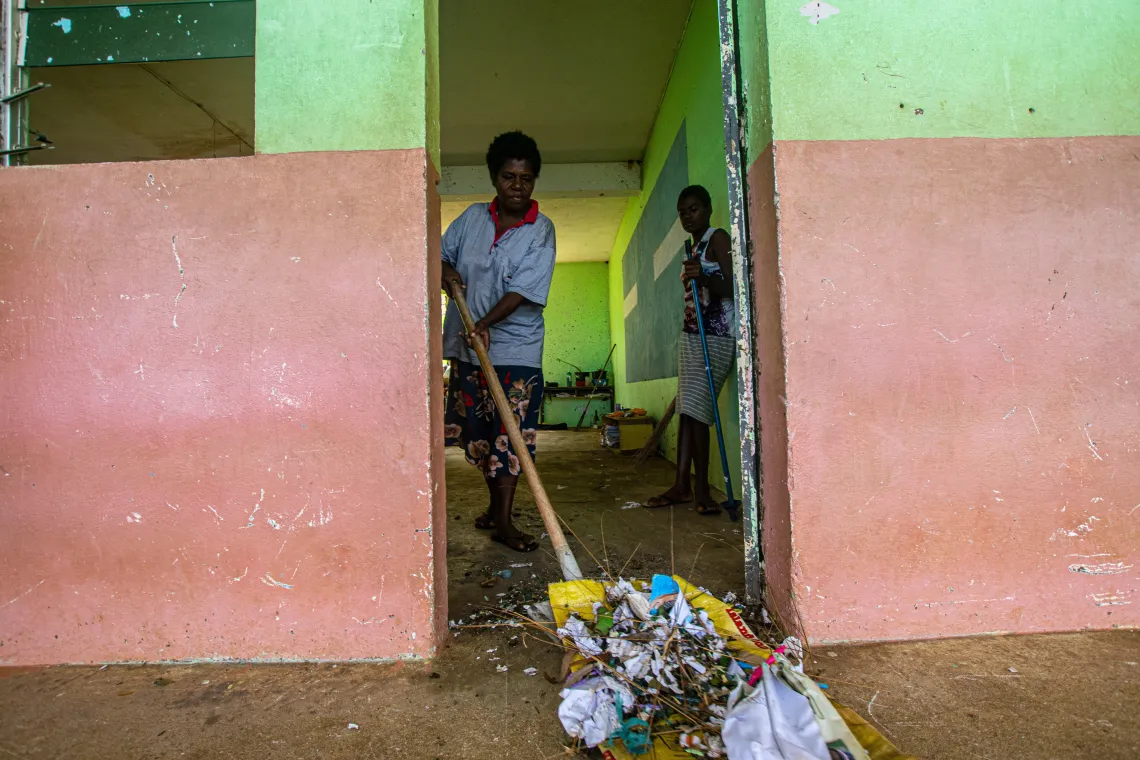 A teacher and one of her student&rsquo;s clean their classroom, after the cyclone.