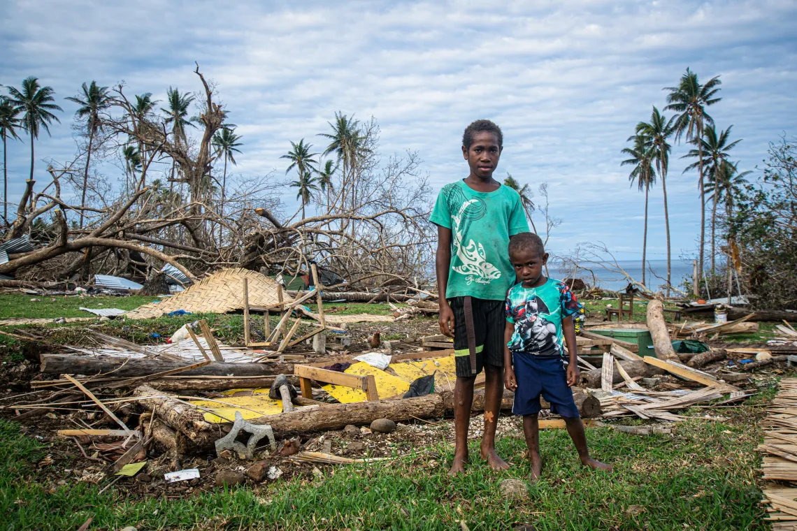 Albertino, 12, and his younger brother Jeremy, 5, stand in front of what used to be their home in Pentecost, Vanuatu.