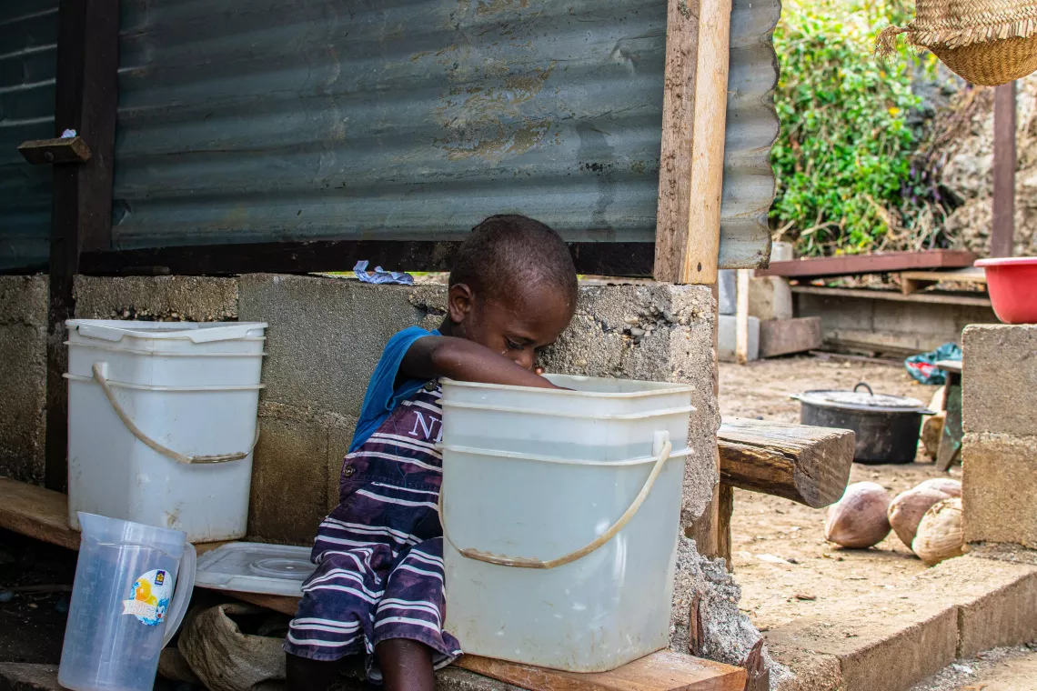 Nicky, 4, fetches water from a bucket to drink.