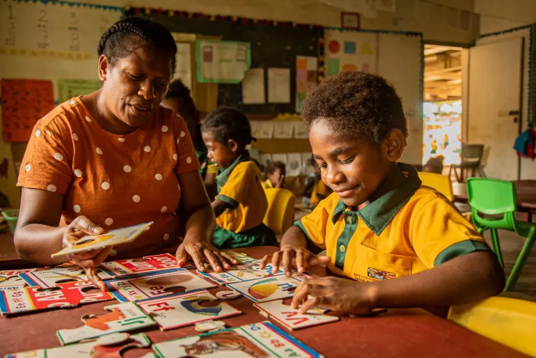 A child living with disability, being assisted by a special needs teacher in a mainstream classroom in Freswota, Port Vila, Vanuatu
