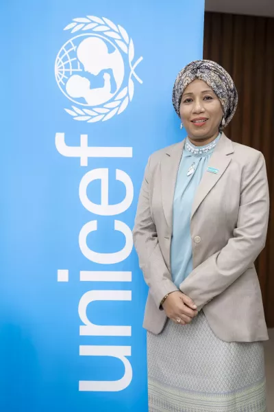A portrait of UNICEF Deputy Representative in Pakistan in front of a large UNICEF branded standee.