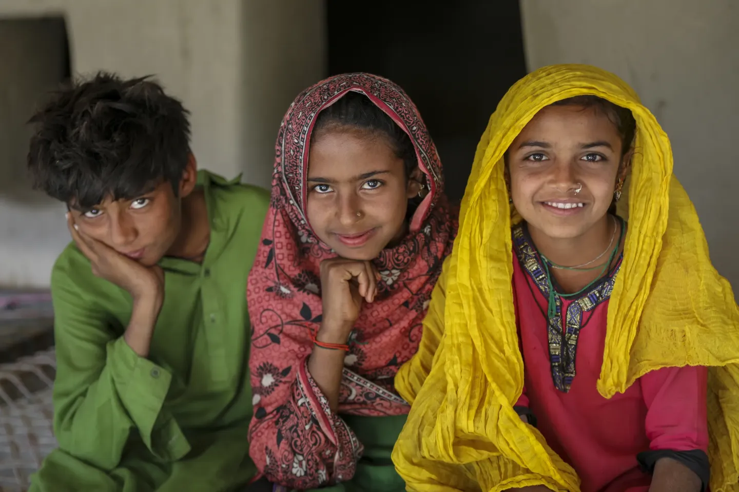 Bakhta (10 right to left) Sajna (11) and Sajjad smile into the camera, Sajawal.