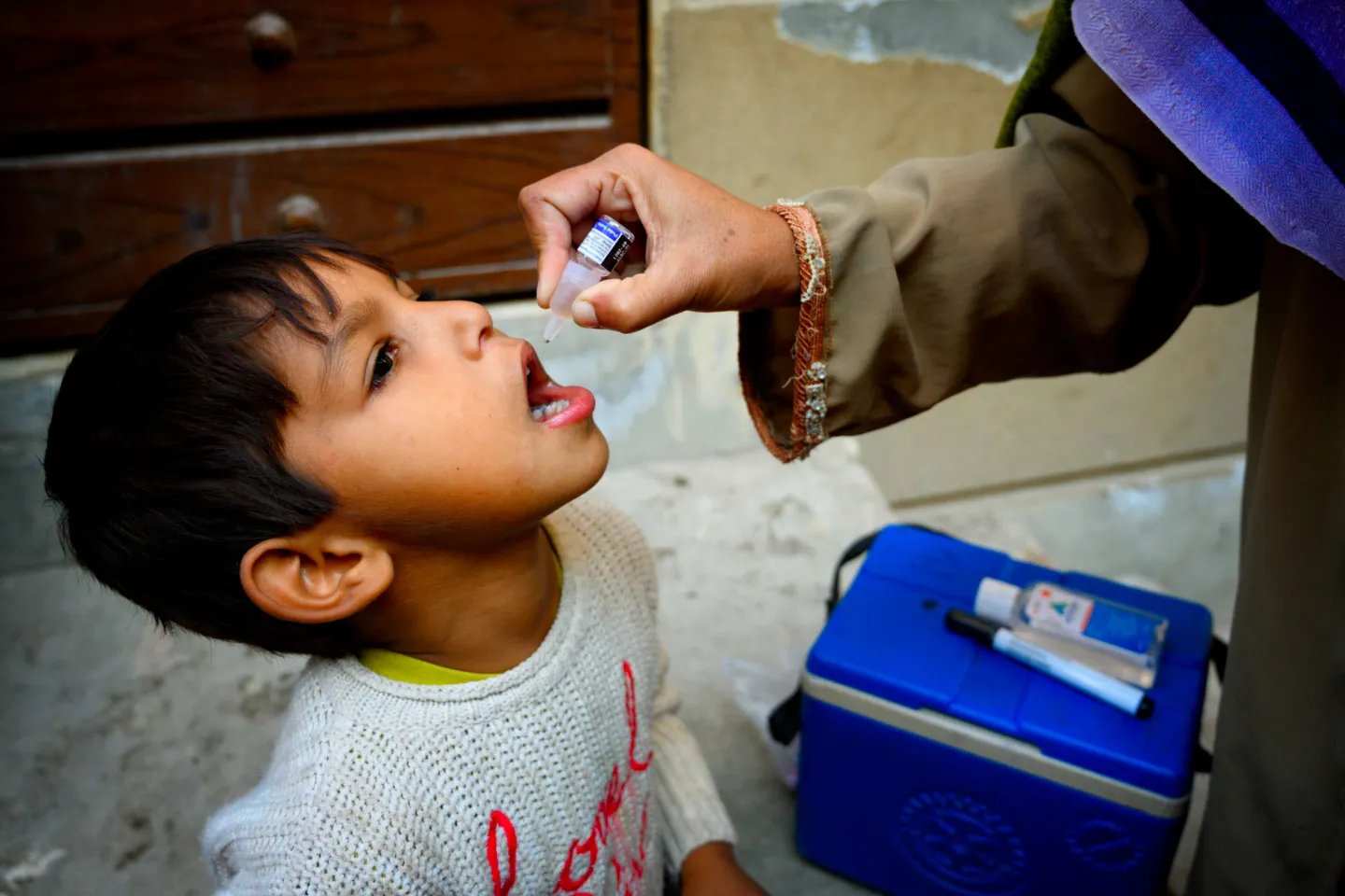 A five year old boy receives the polio vaccine from Shumaila, a polio vaccinator in Lahore.
