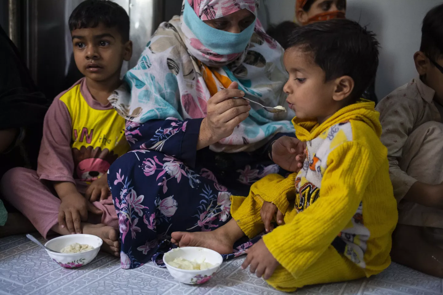 A woman feeds her three year old son a rice porridge