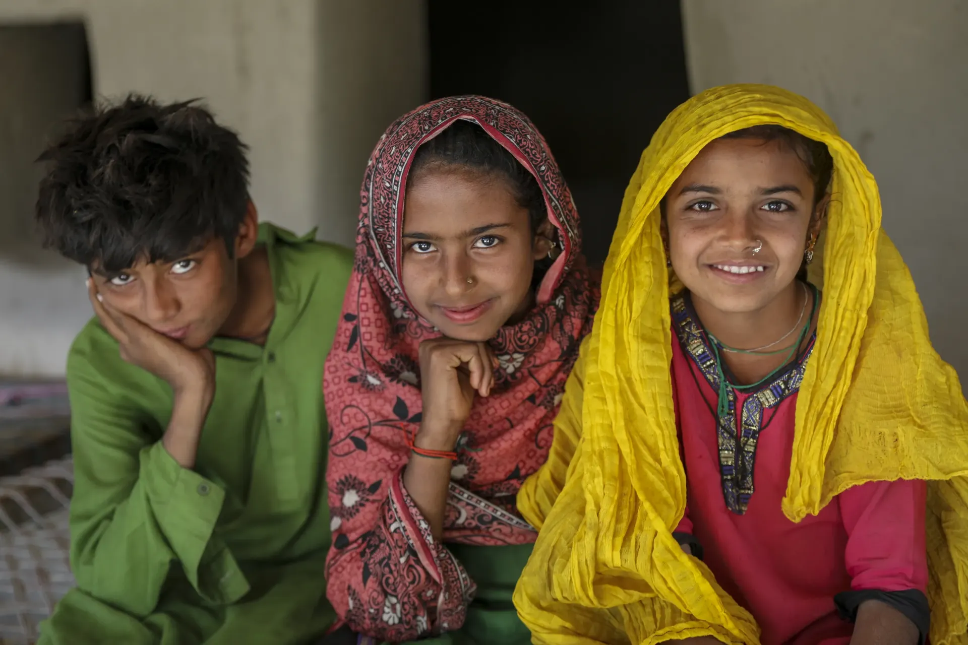 Bakhta (10 right to left) Sajna (11) and Sajjad smile into the camera, Sajawal.
