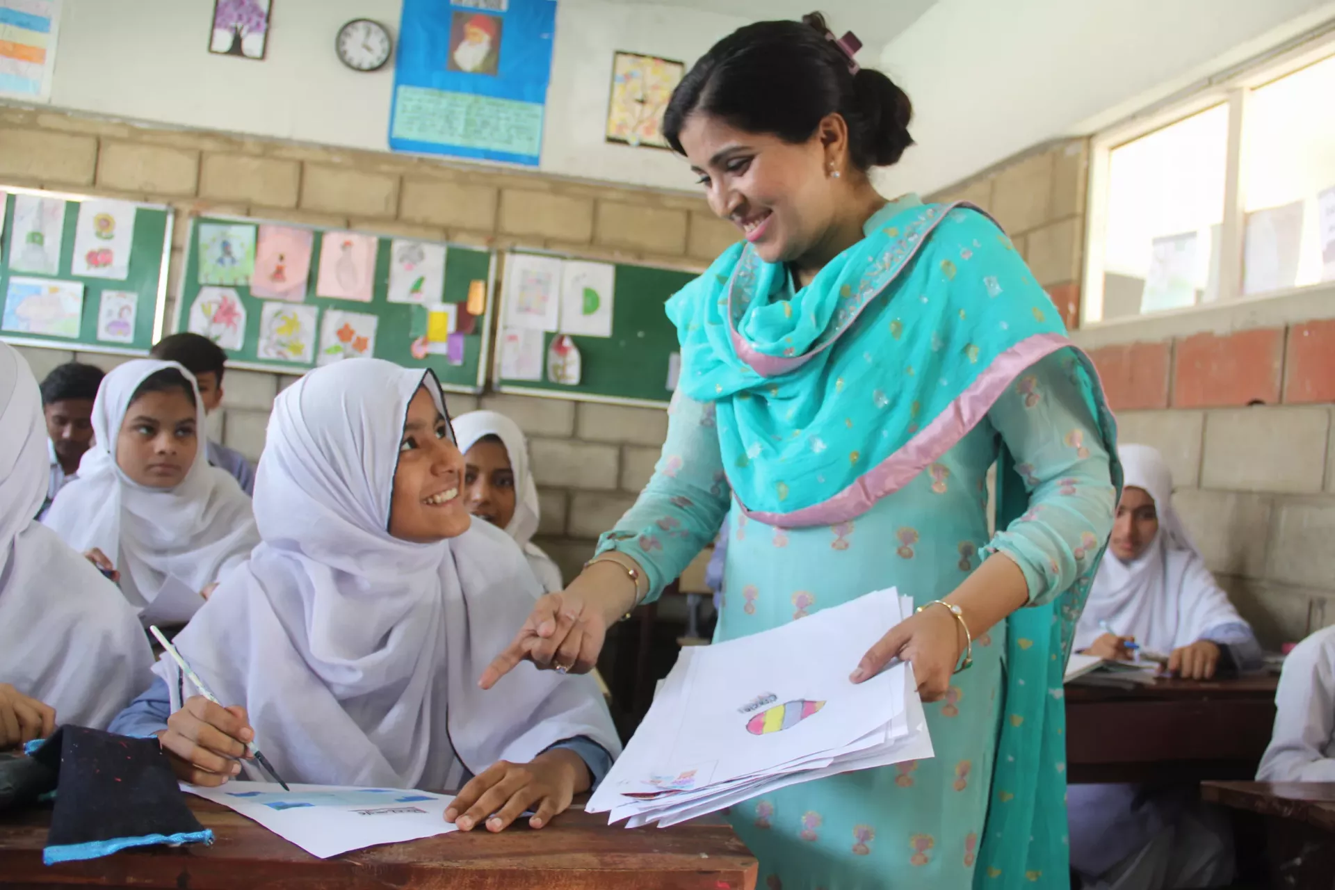 Farzana Sarwar, a teacher trained under the STA-DEEP project, interacts with Javeria during a class session.   