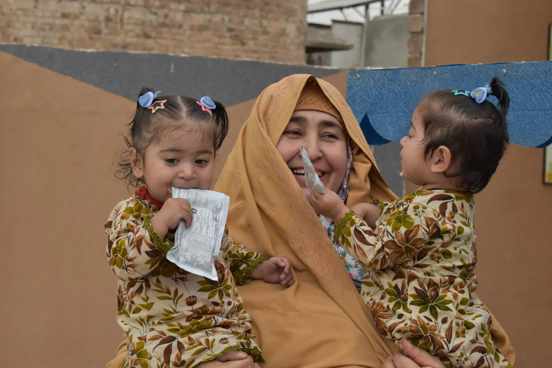 Dilbara Bibi shares a joyful moment with her granddaughters, Safa and Shifa, at the Nazar Bostan Civil Dispensary Peshawar where they received nutrition support and Ready to use therapeutic food (RUTF) on 16 April 2026. 