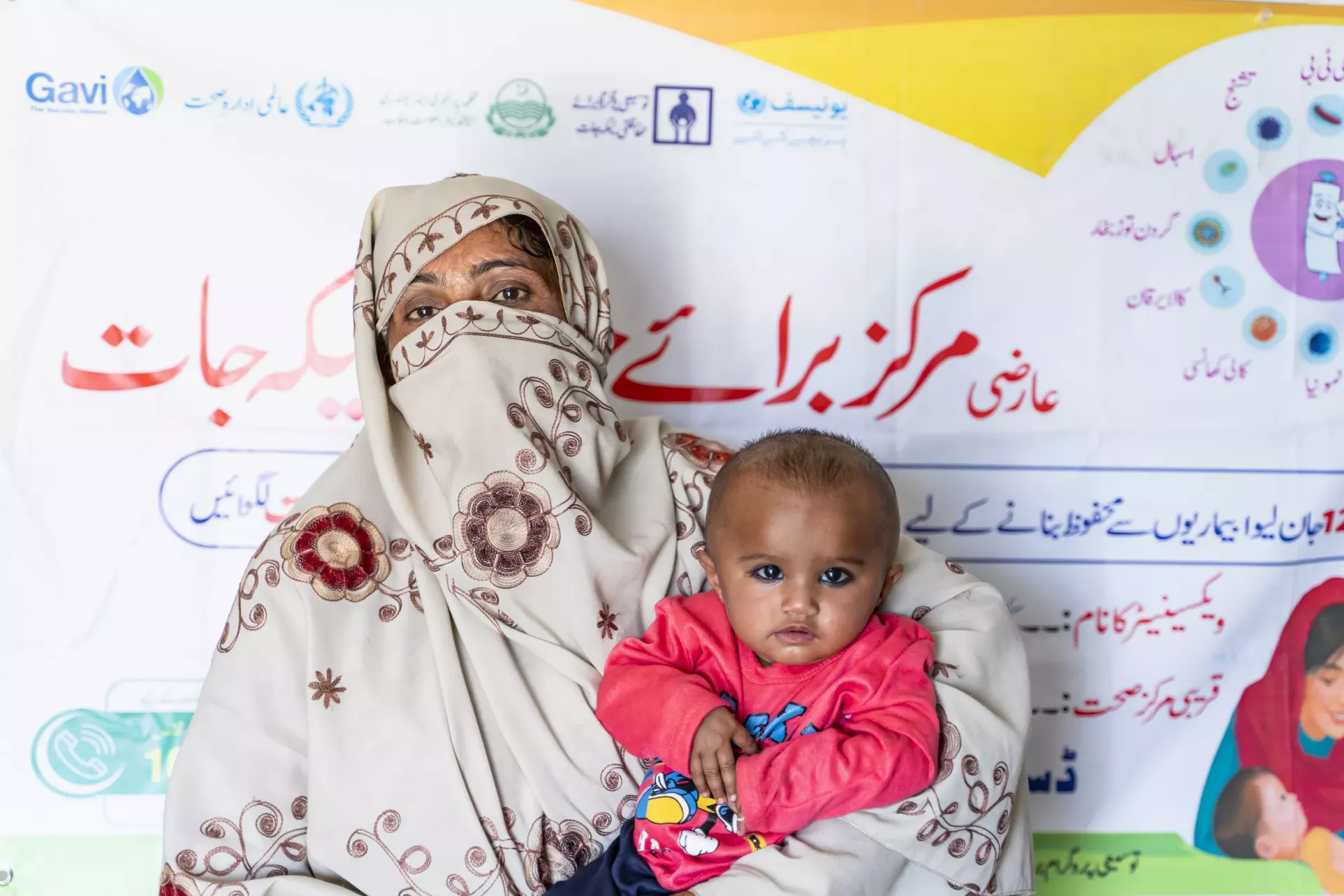 Baby Husna sits in her mother&rsquo;s lap as they wait for her turn to be immunized.