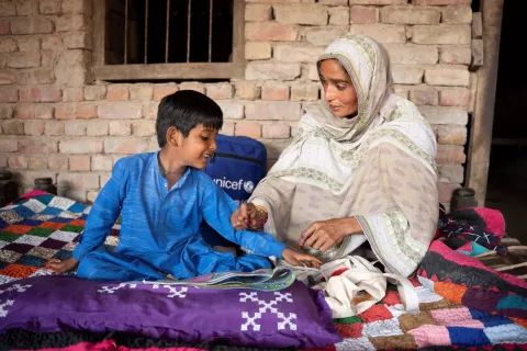 Muhammad Ehsan (7) explores the colouring book with his mother Rehana. Colouring books are one of the items in a psychosocial support (PSS) kit full of toys, games and activity based books that UNICEF provided to children and families in areas affected by the 2022 floods.  