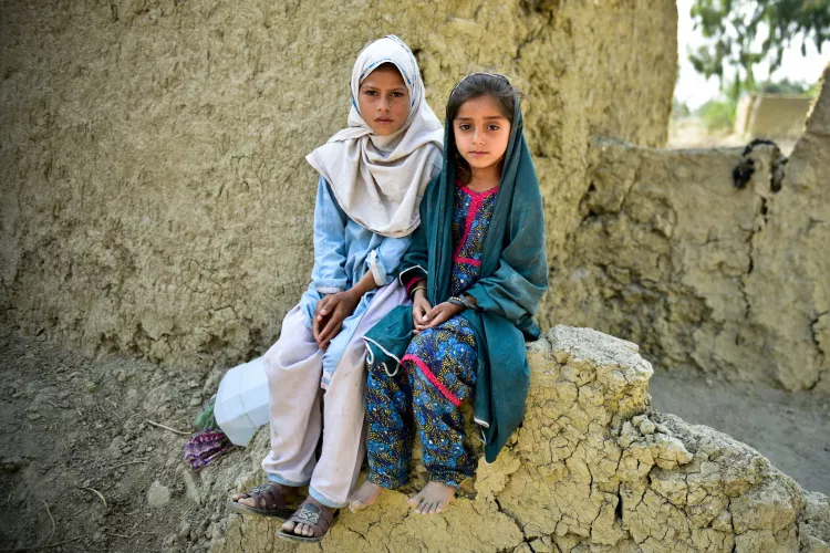 Muriko Bibi (7) and Tehseen (6) sit on the damaged wall of their mud house which was almost destroyed during the 2022 floods in Pakistan. They belong to village Chitool, Rajanpur district of South Punjab province, Pakistan.