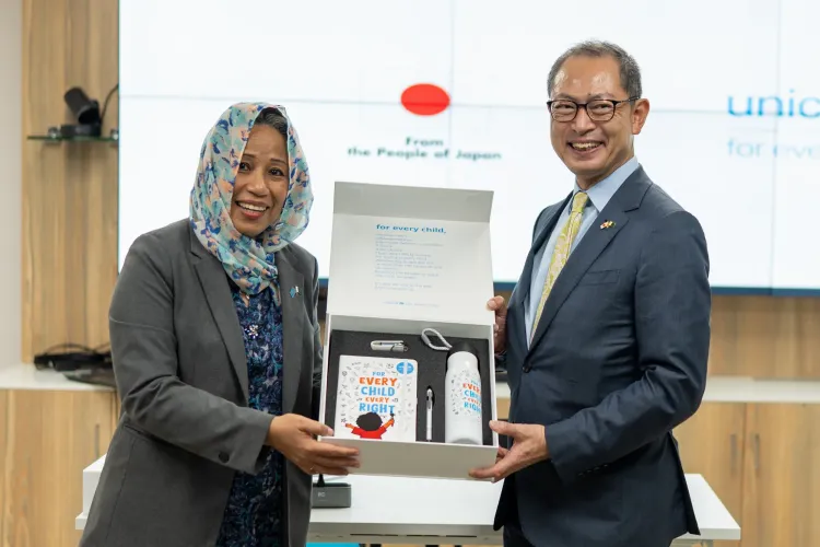 woman hands a box of unicef memorabilia to man
