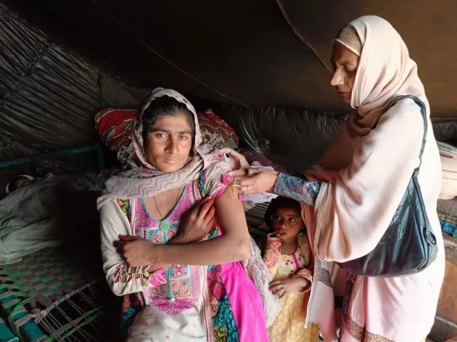 Babra (36) getting vaccinated by a UNICEF supported Lady Health Worker.