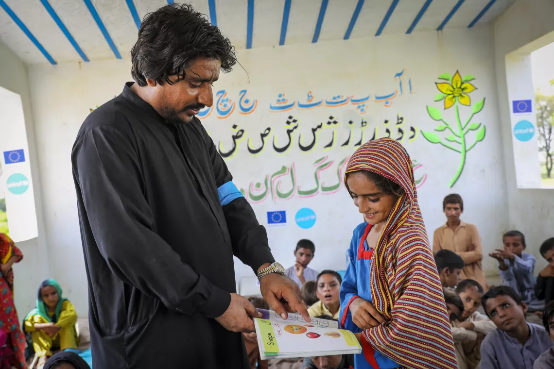 Nadia (8) happily seeks her teacher’s help to understand a lesson at the Temporary School Structure, Lajawab (village) in Jaffarabad district of Balochistan. 