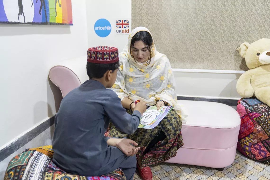 Psychologist Maria Sultan encourages a child to colour while taking a session in the Counselling Room at the Child Protection Unit in Mingora, Swat District, Khyber Pakhtunkhwa.