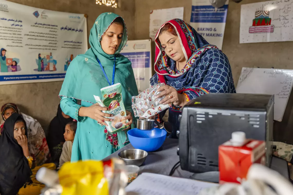 Aru Mehdi (right), a trainer from the Hashoo Foundation, is guiding Ayatul (left) on mixing ingredients to bake a cake.
