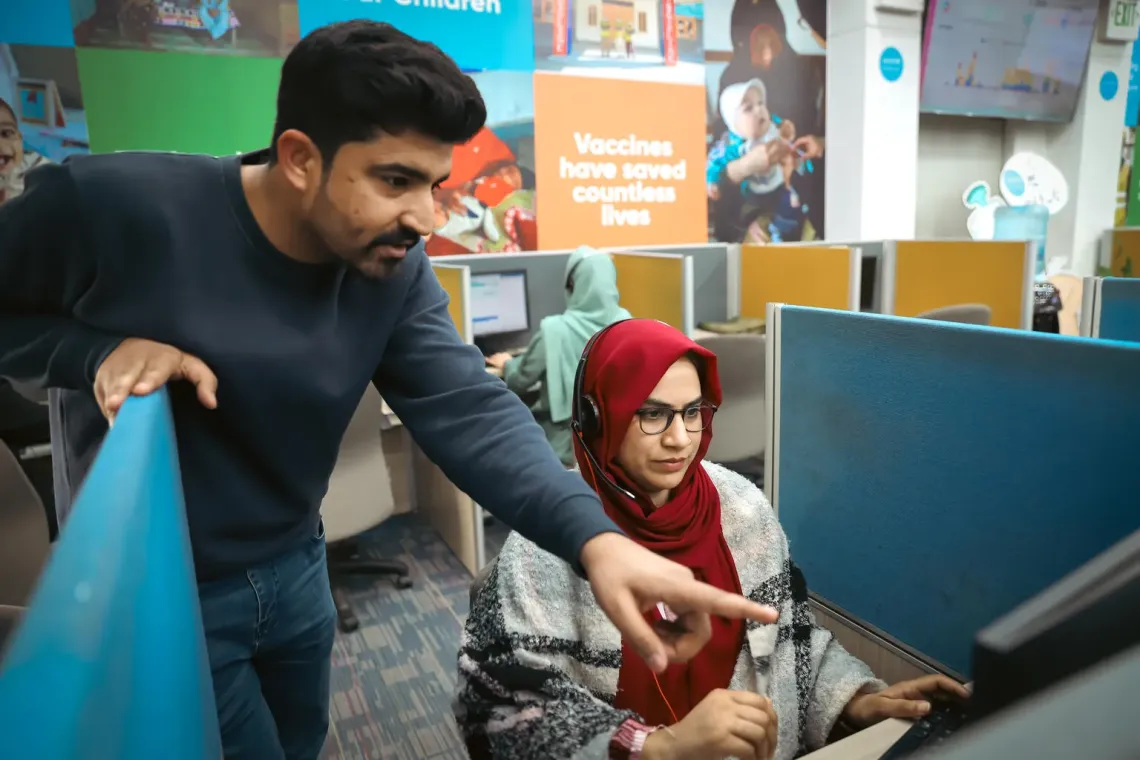 Kamran, Team Coach, guides Sumaira Rabbani, an agent at Sehat Tahaffuz-1166 call centre in Islamabad, Pakistan.