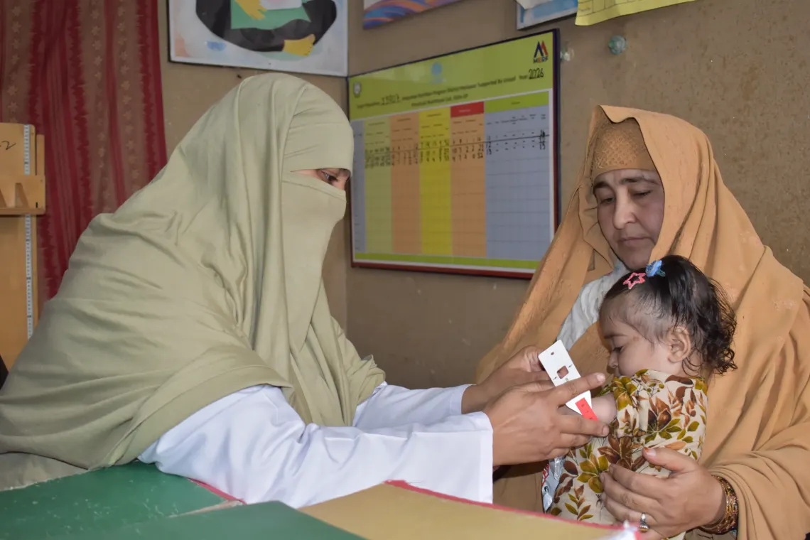Nutrition Assistant Sehrish at the Civil Dispensary Peshawar measuring Safa&rsquo;s growth with a Mid-Upper Arm Circumference (MUAC) tape on her visit to the UNICEF-supported facility. 