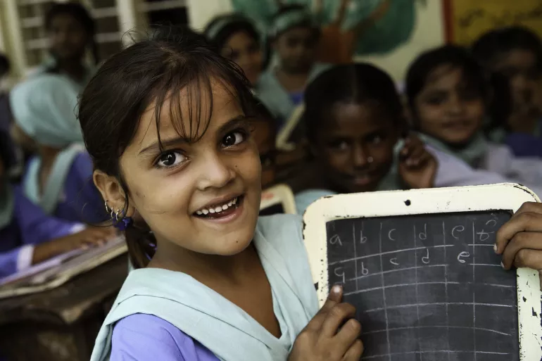 The image shows a girl writing on a small blackboard