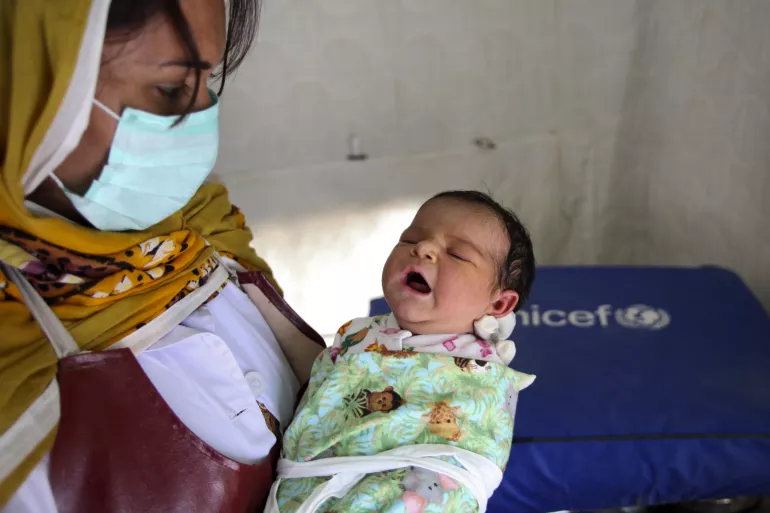A lady health worker holds a newborn baby